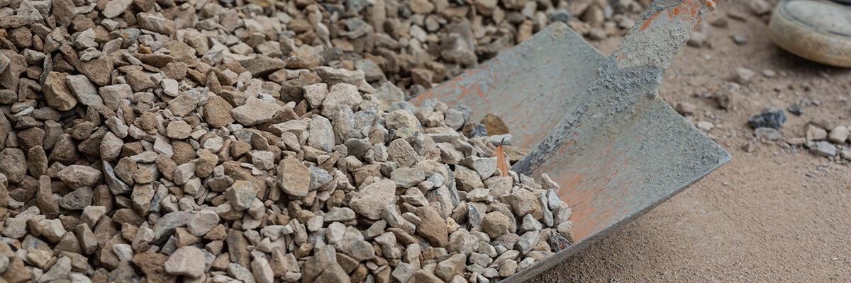 Shovel moving gravel off of concrete foundation.